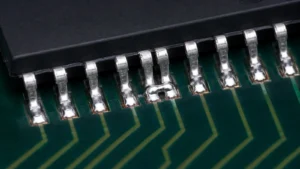 Solder bridge connecting two adjacent fine-pitch IC leads while neighboring solder joints remain separate