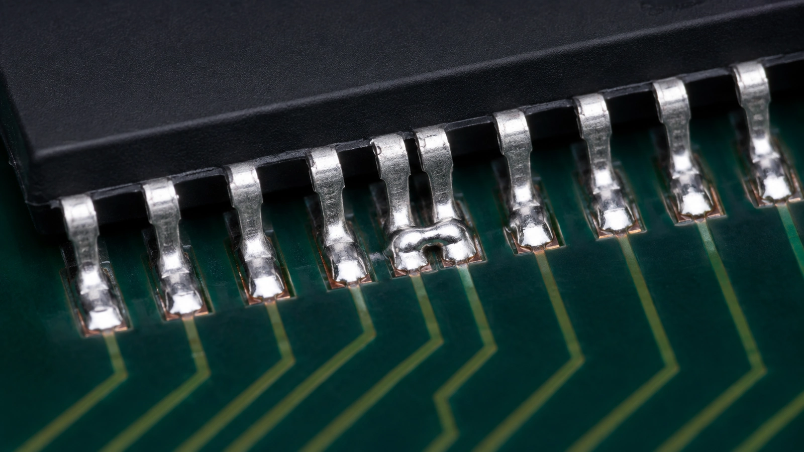 Solder bridge connecting two adjacent fine-pitch IC leads while neighboring solder joints remain separate